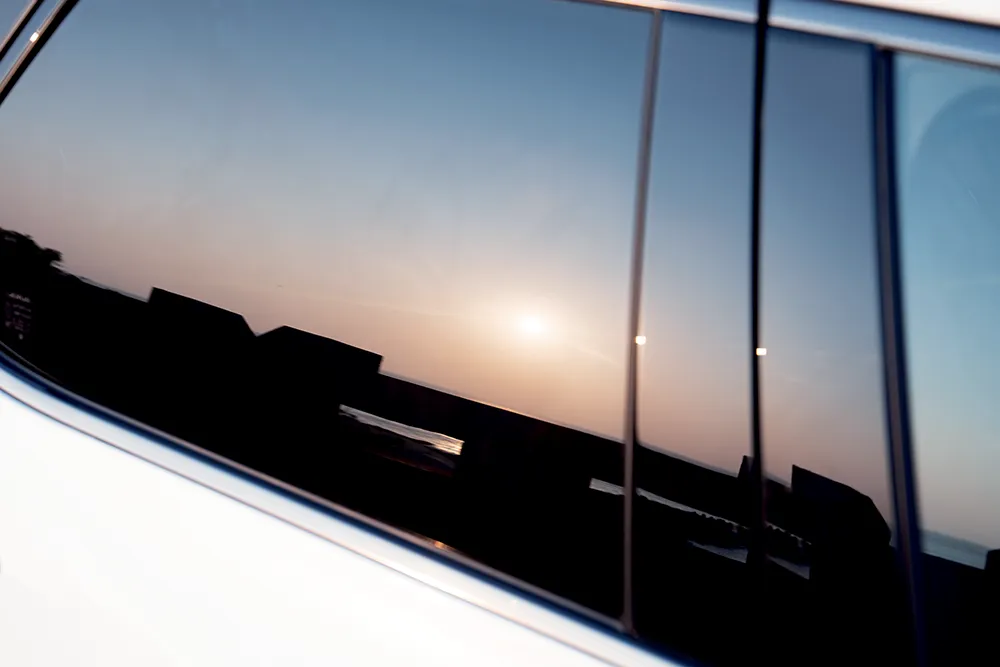 從Lexus NX 450h+的車窗，反射夕陽